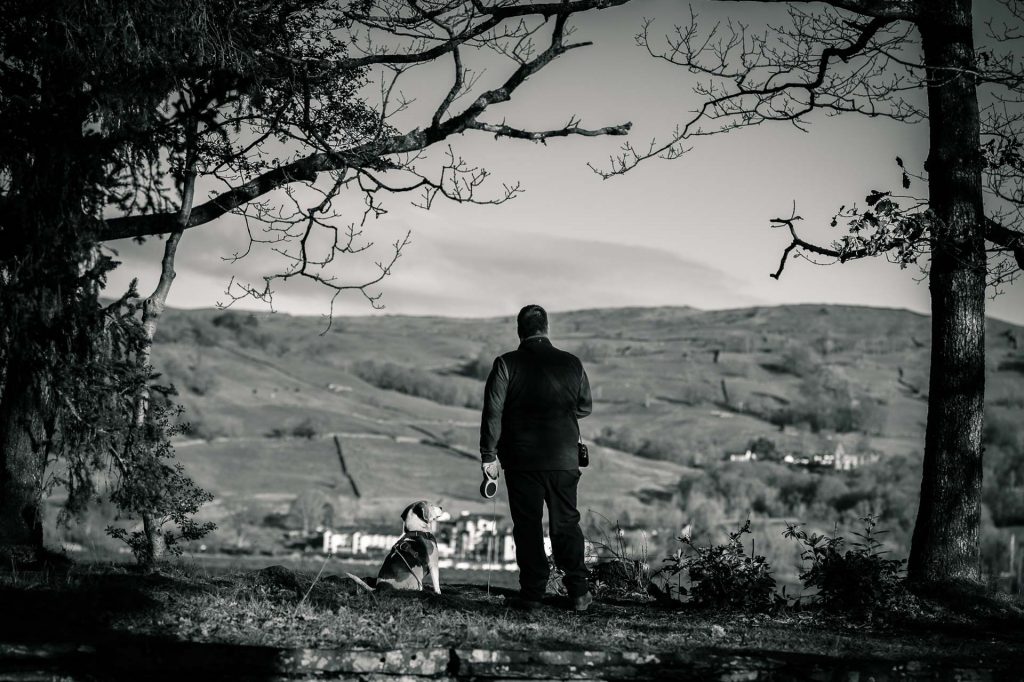Man and dog looking over water in black and white